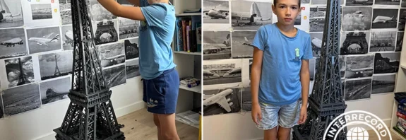 8-year-old holding completed Eiffel Tower model