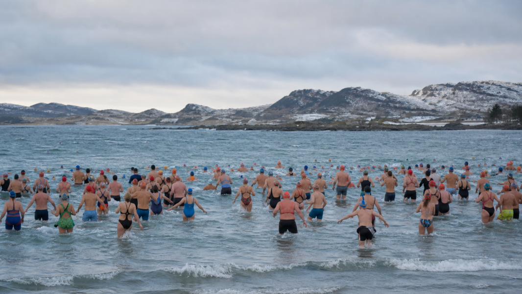 Участники массового зимнего заплыва в холодной воде на побережье Ølberg в Норвегии