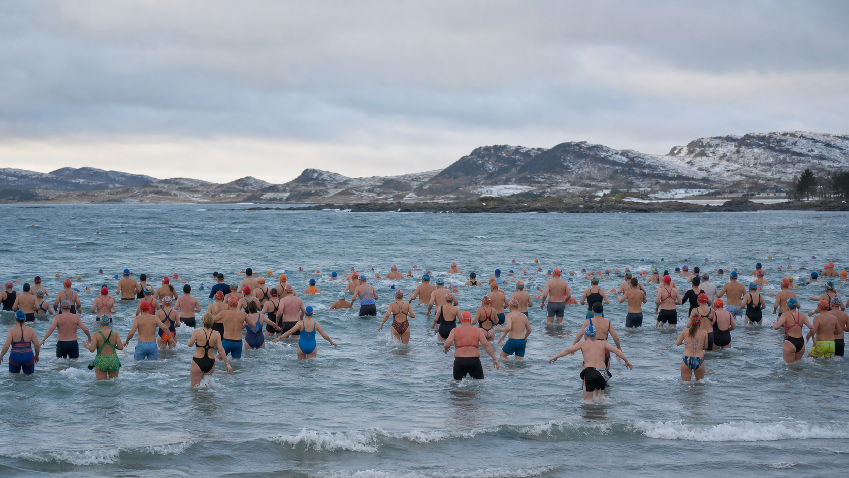 Участники массового зимнего заплыва в холодной воде на побережье Ølberg в Норвегии