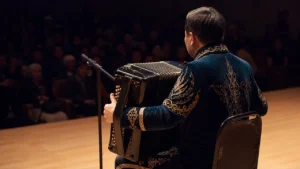 Казахский музыкант с баяном на сцене во время длительного выступления